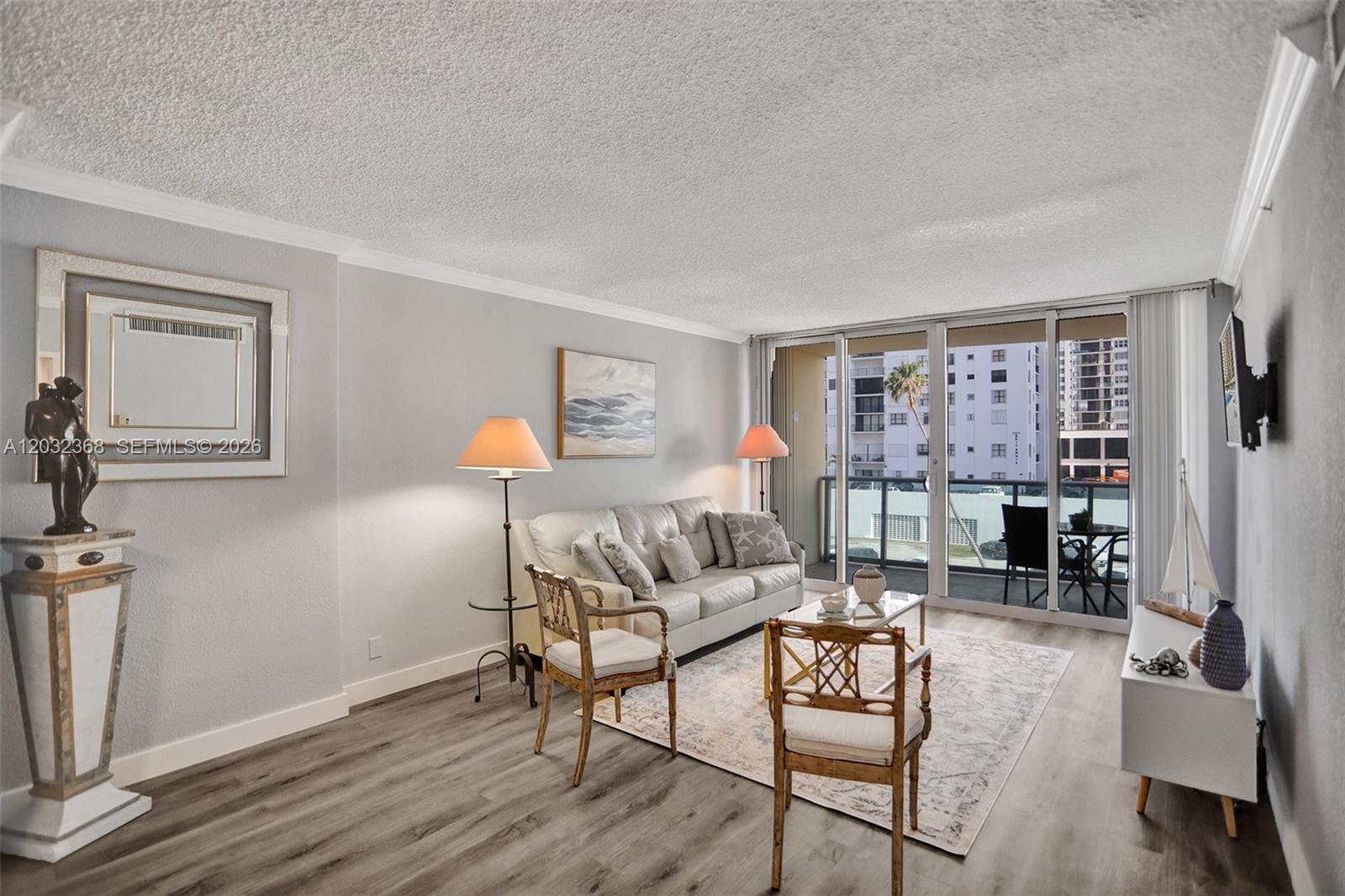 A living room features a white sofa, two wooden chairs, and a balcony with city views — 2501 S Ocean Dr # 302, Hollywood FL 33019, HOLLYWOOD, FL