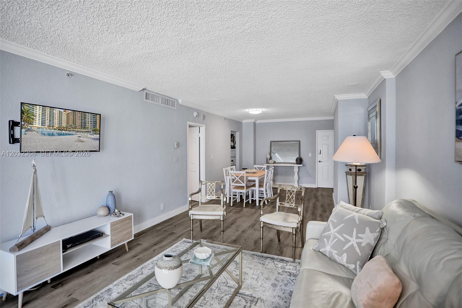 This living and dining area features light blue walls, wood-look flooring, and a popcorn ceiling — 2501 S Ocean Dr # 302, Hollywood FL 33019, HOLLYWOOD, FL