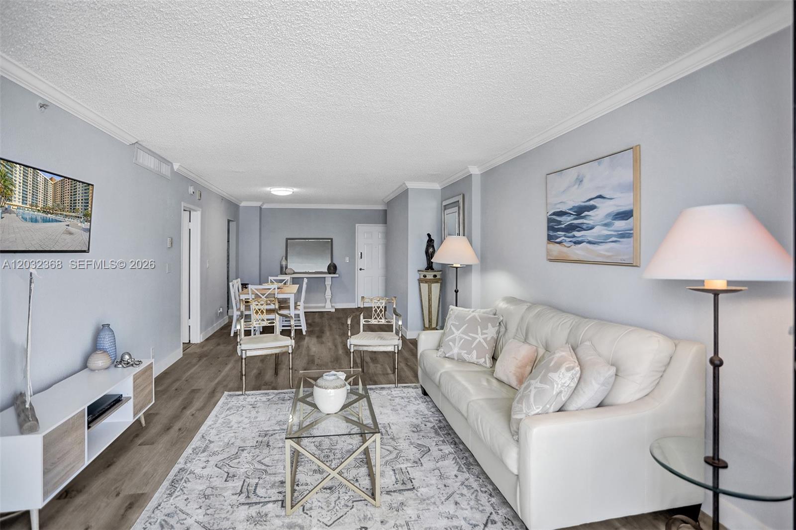 A living room with light gray walls, wood-look flooring, a white sofa, and a dining area — 2501 S Ocean Dr # 302, Hollywood FL 33019, HOLLYWOOD, FL