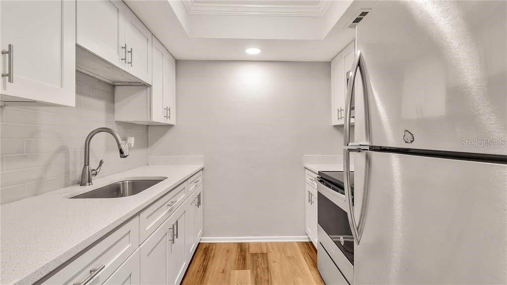 A galley kitchen features white cabinets, stainless steel appliances, and light-colored countertops — 5900 22nd Ave N 5900 22ND AVE N UNIT 1 UNIT 1, ST PETERSBURG, FL