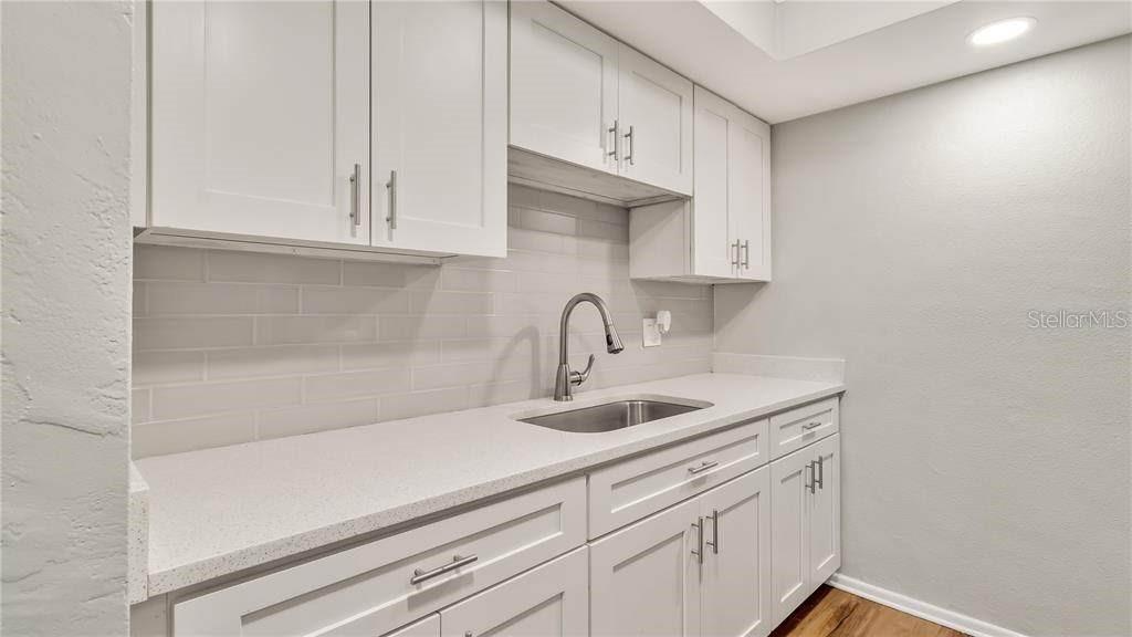 A kitchen features white cabinets, a light countertop, a stainless steel sink, and subway tile — 5900 22nd Ave N 5900 22ND AVE N UNIT 1 UNIT 1, ST PETERSBURG, FL