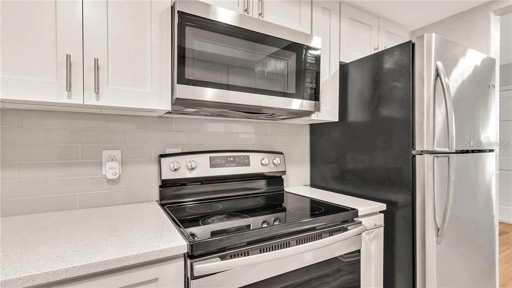 A kitchen features white cabinets, a stainless steel microwave, a glass-top stove, and a refrigerator — 5900 22nd Ave N 5900 22ND AVE N UNIT 1 UNIT 1, ST PETERSBURG, FL