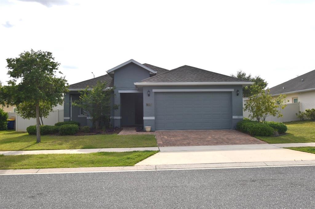 A single-story house with a gray exterior, a two-car garage, and a paved driveway — 709 CALABRIA WAY, HOWEY IN THE HILLS, FL