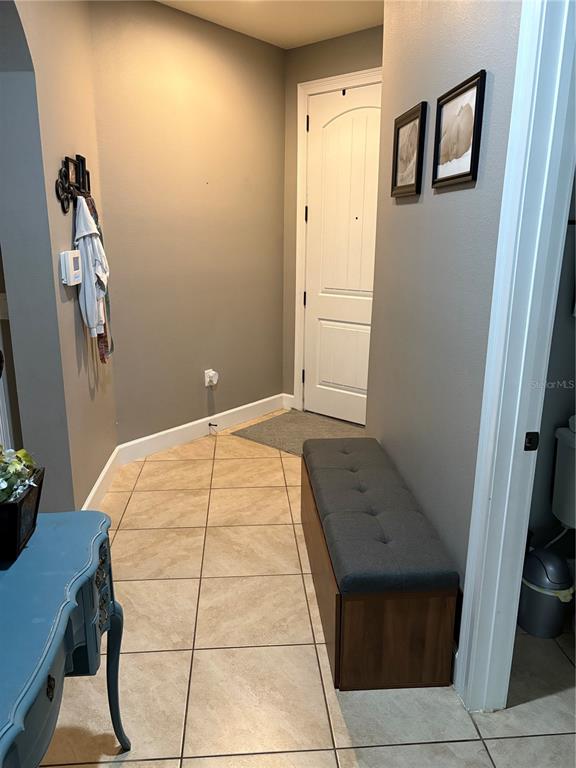 A tiled entryway features a gray storage bench, a blue console table, and a white door — 709 CALABRIA WAY, HOWEY IN THE HILLS, FL