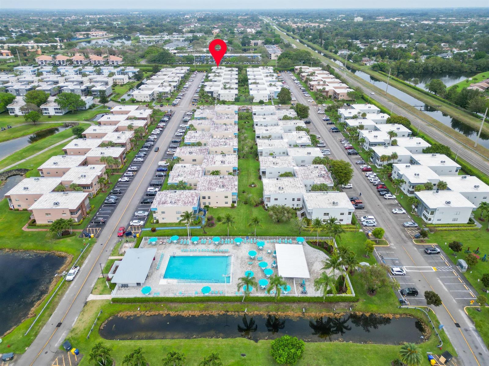 Aerial view of a multi-building residential complex featuring a central swimming pool and parking — 362 Burgundy H, Delray Beach FL 33484, DELRAY BEACH, FL