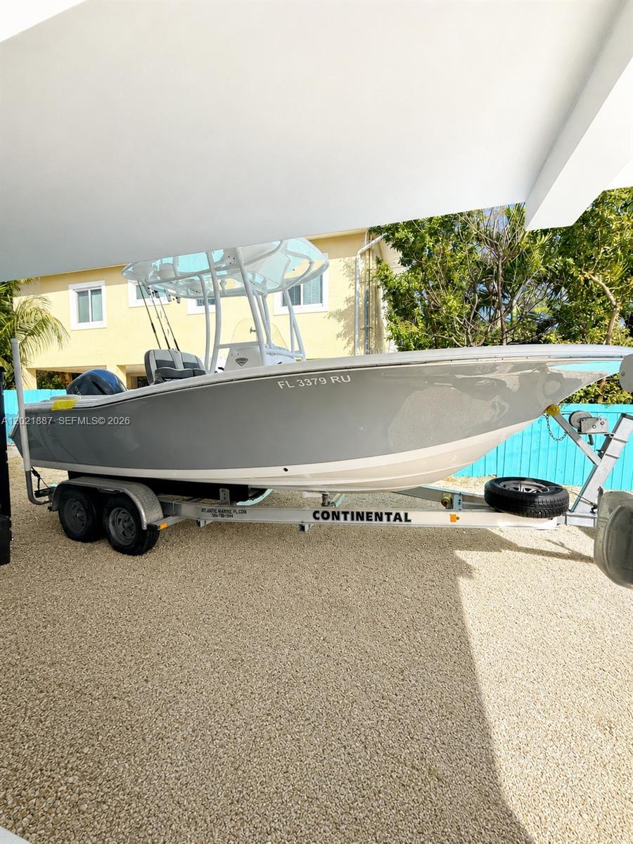 A gray center console boat sits on a trailer in a gravel driveway — 414 Coconut Dr, Key Largo FL 33037, KEY LARGO, FL