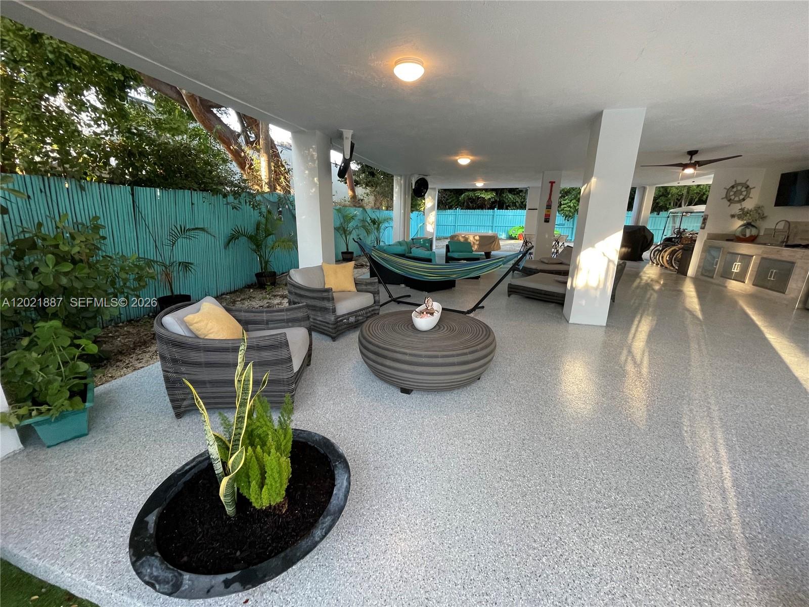 A covered outdoor patio features gray wicker furniture, a hammock, and a speckled concrete floor — 414 Coconut Dr, Key Largo FL 33037, KEY LARGO, FL