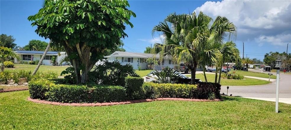 A large tree and palm tree stand in a landscaped yard before a residential house — 6307 FORDHAM PLACE, BRADENTON, FL