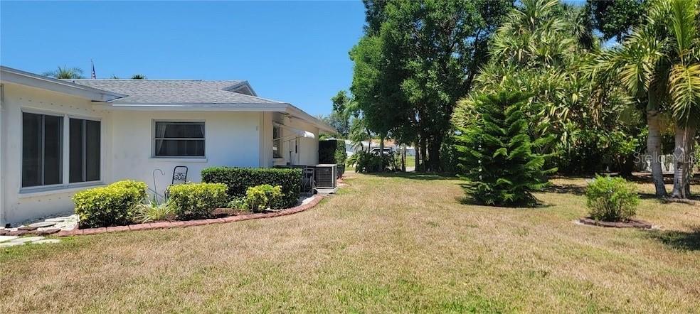 A white house with a gray roof sits next to a large, grassy yard — 6307 FORDHAM PLACE, BRADENTON, FL