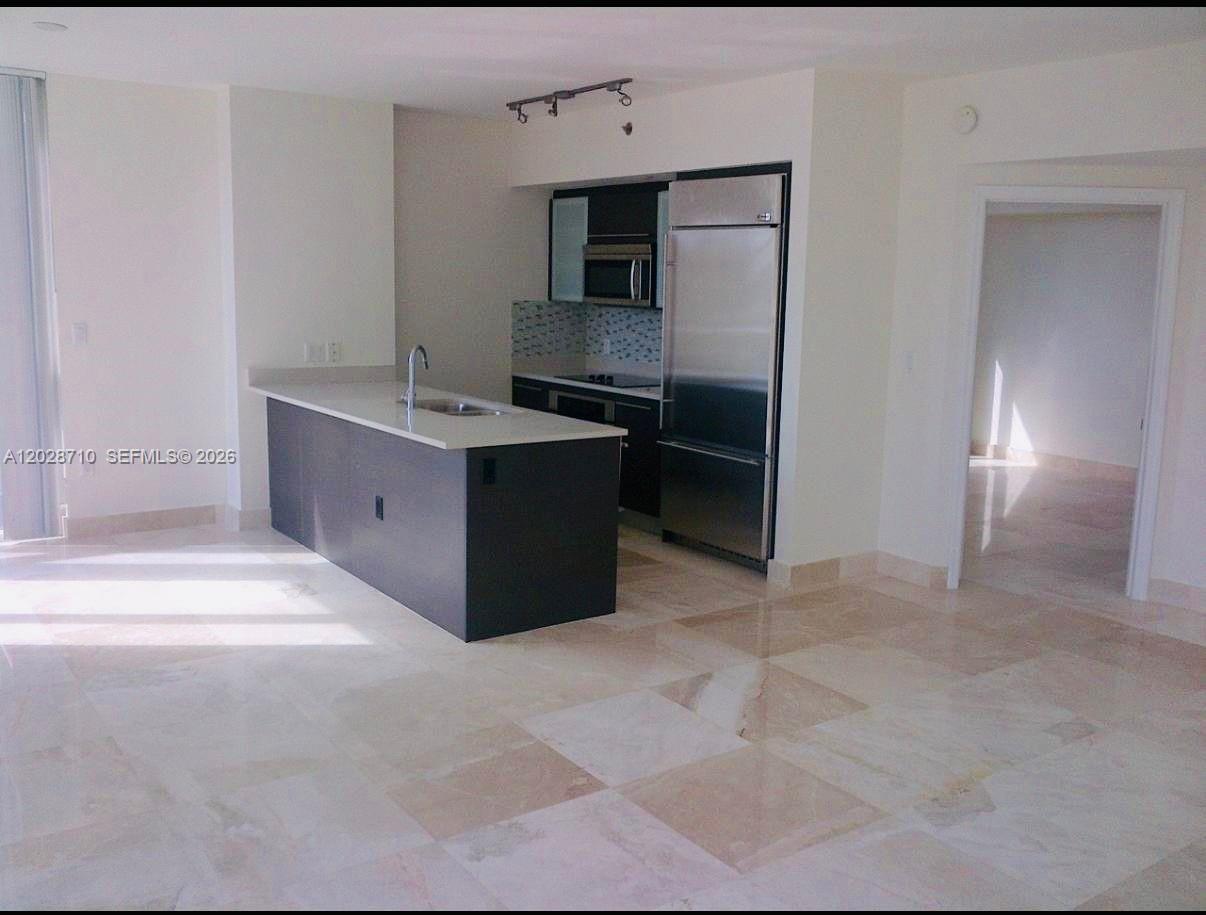 An open-concept kitchen with dark cabinetry and an island sits in a room with tile floors — 55 SE 6th St # 1502, Miami FL 33131, MIAMI, FL