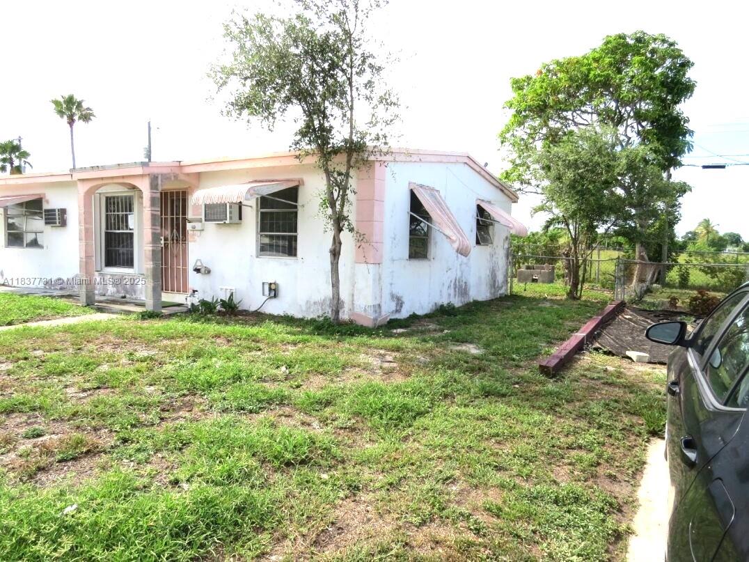 A single-story white house with pink trim and window awnings sits on a grassy lot — 525 NW 16th St, Pompano Beach FL 33060, POMPANO BEACH, FL