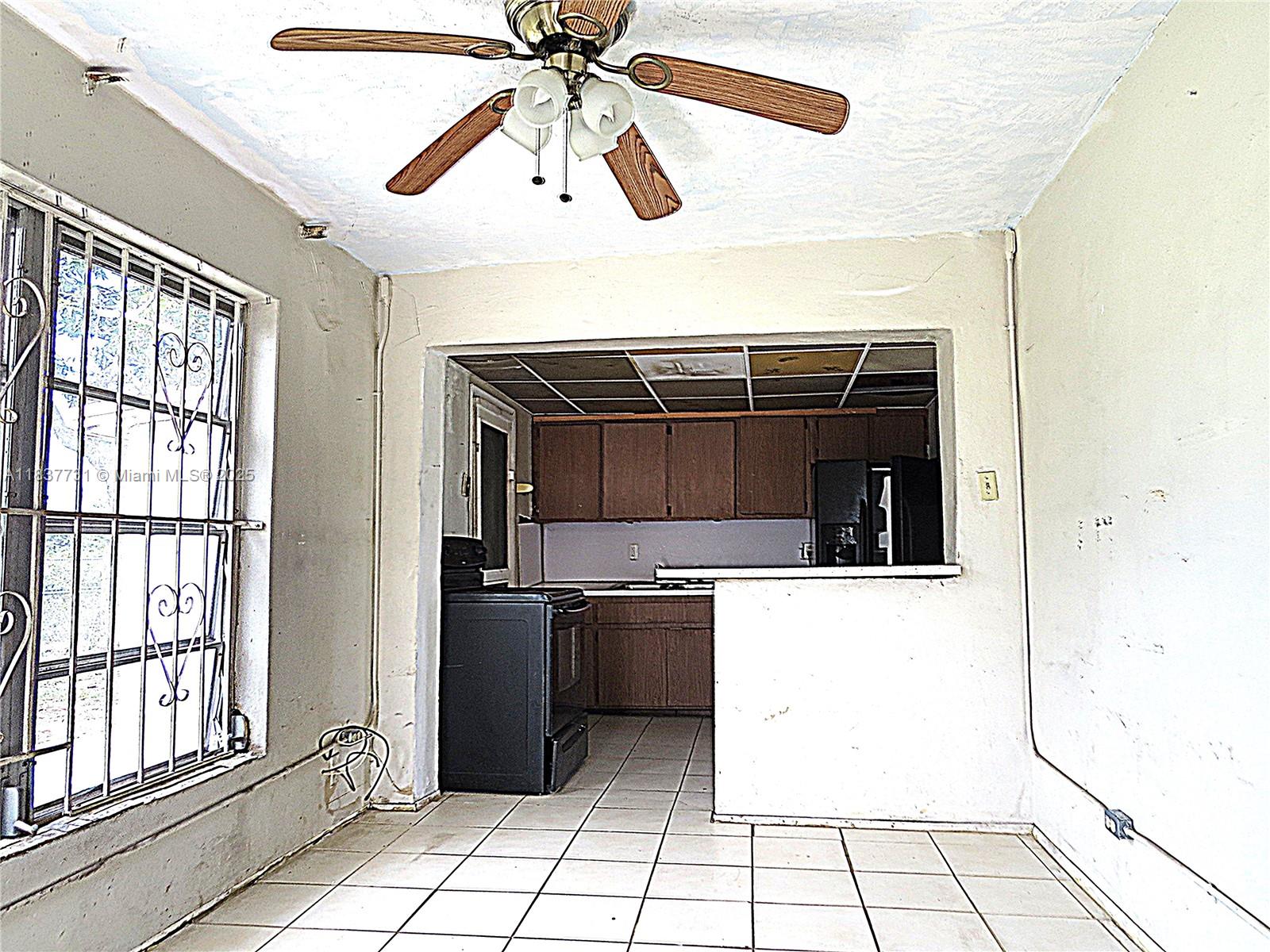A kitchen with dark cabinets and a black stove opens into a tiled dining area — 525 NW 16th St, Pompano Beach FL 33060, POMPANO BEACH, FL