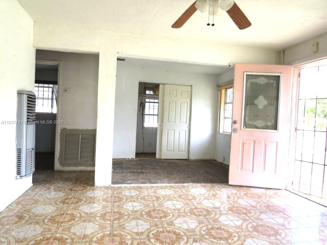 An interior view shows a tiled room with a pink door and a ceiling fan — 525 NW 16th St, Pompano Beach FL 33060, POMPANO BEACH, FL
