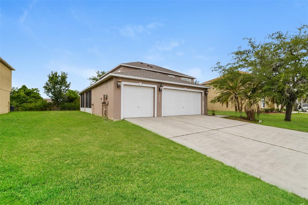 A tan two-story house features a two-car garage and a large grassy front yard — 2361 ANDREWS VALLEY DRIVE, KISSIMMEE, FL