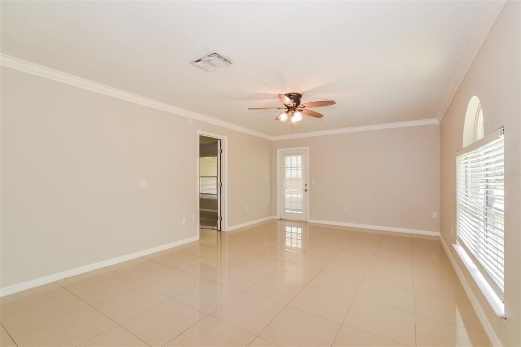 A bright, empty room with beige tile floors, a ceiling fan, and a glass-paneled door — 2361 ANDREWS VALLEY DRIVE, KISSIMMEE, FL