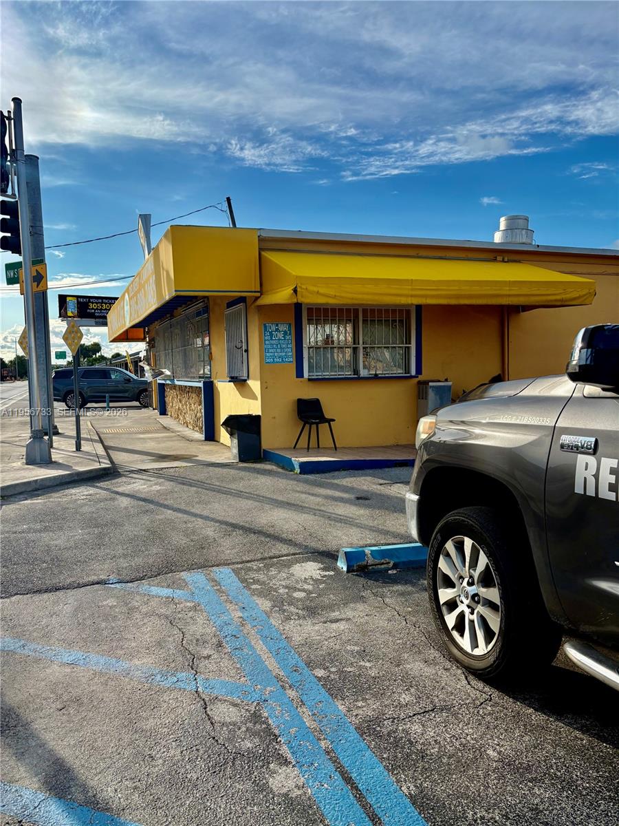 A yellow commercial building with a metal awning and a parking lot in the foreground — 8401 NW South River Dr, Medley FL 33166, MEDLEY, FL