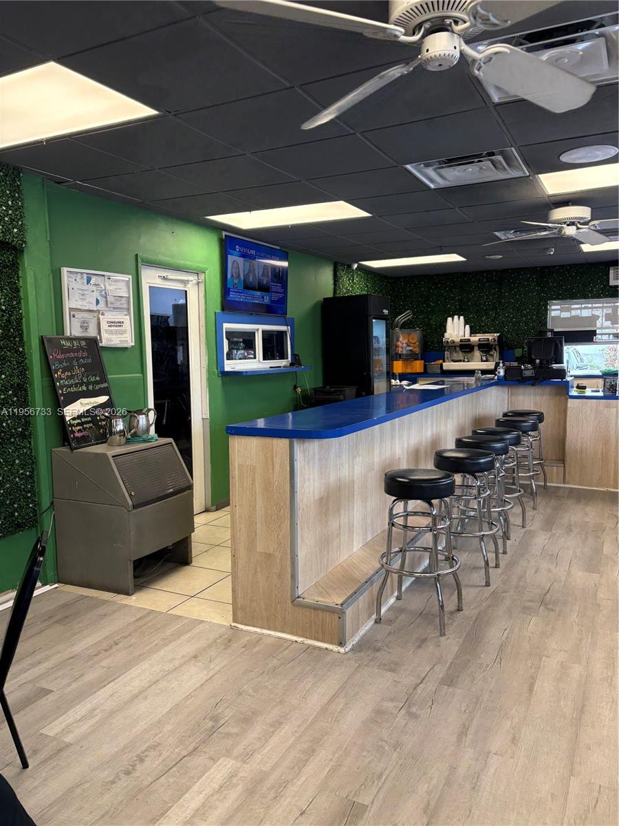 A commercial cafe interior features a blue-topped bar with stools and green accent walls — 8401 NW South River Dr, Medley FL 33166, MEDLEY, FL