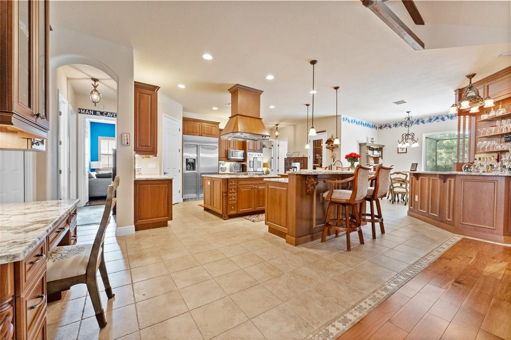 A spacious kitchen features wood cabinetry, a large center island, and tile flooring — 509 VINTAGE WAY, BRANDON, FL