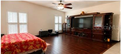 A bedroom features dark wood flooring, a large entertainment center, and a patterned bedspread — 1858 N PRAIRIE DUNES COURT, OVIEDO, FL
