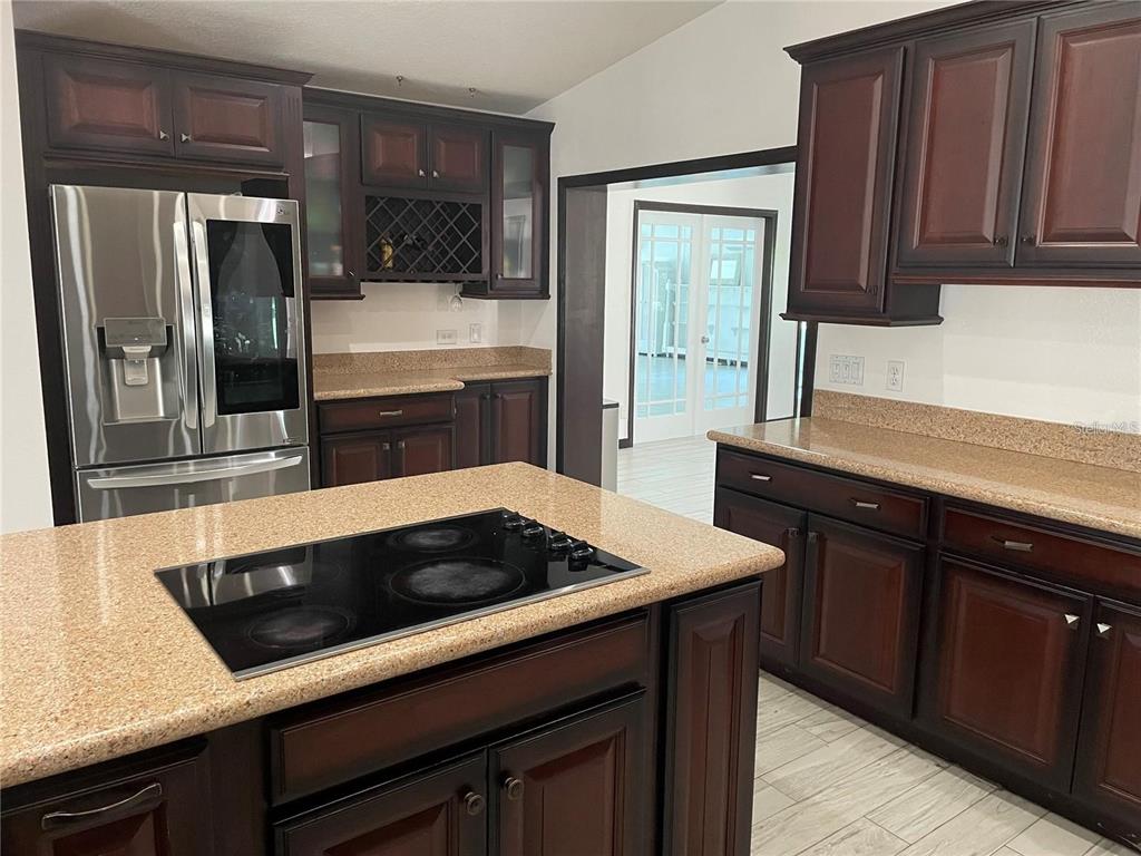 A kitchen features dark wood cabinets, granite countertops, a center island, and stainless steel appliances — 1858 N PRAIRIE DUNES COURT, OVIEDO, FL