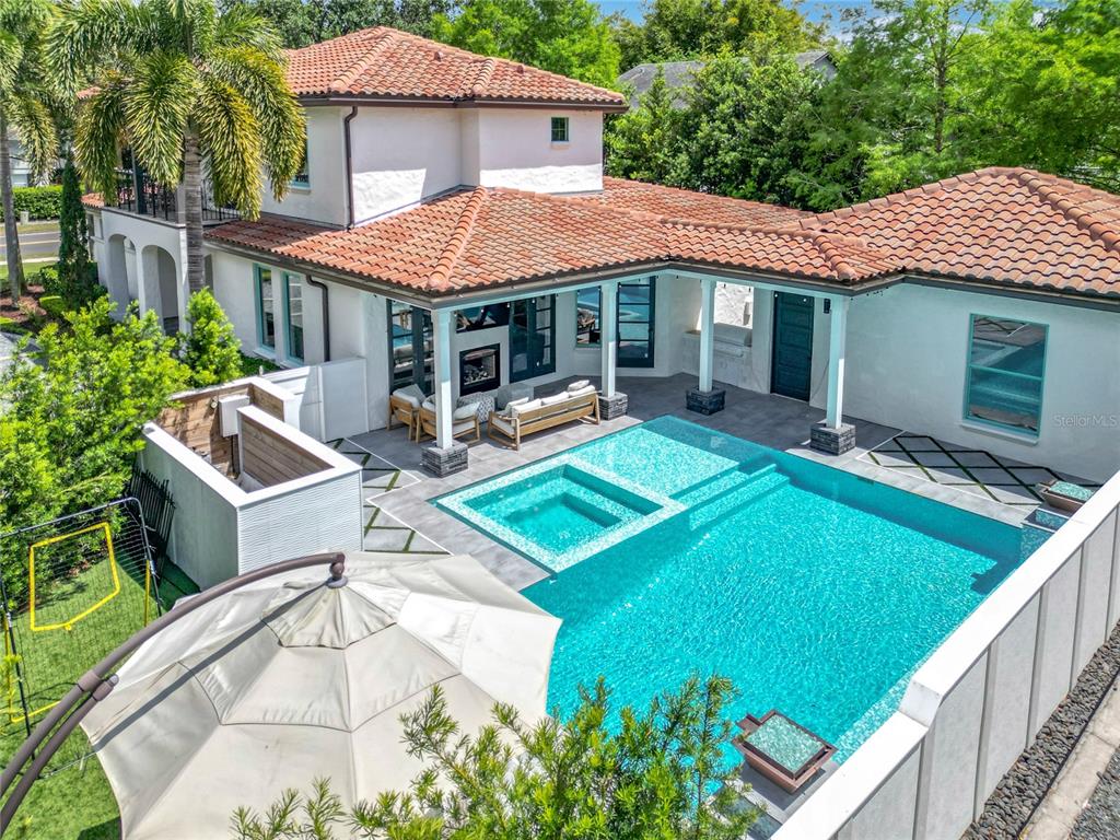 An aerial view of a backyard featuring a swimming pool, spa, and covered patio area — 2614 PARKLAND DRIVE, WINTER PARK, FL