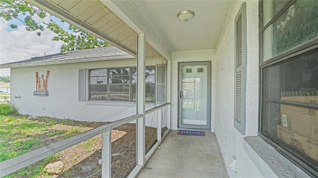 A covered front porch with a screen enclosure leads to a white front door — 774 HARLAND COURT, KISSIMMEE, FL