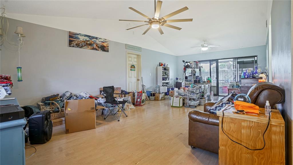 A living room with light wood flooring, a vaulted ceiling, and a brown leather recliner — 774 HARLAND COURT, KISSIMMEE, FL