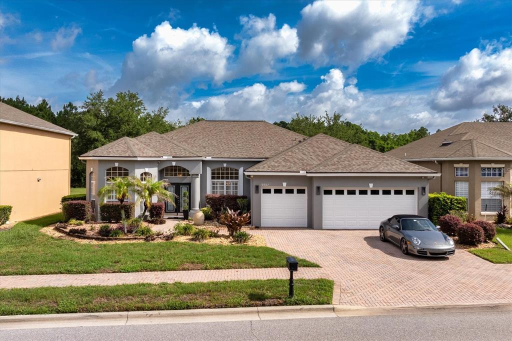 A single-story house with a gray exterior, a brick driveway, and a two-car garage — 9997 CHARDONNAY DRIVE, ORLANDO, FL