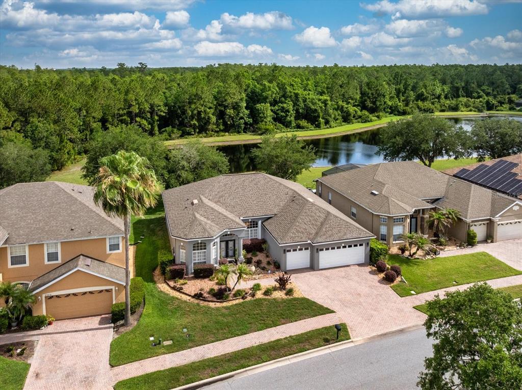 An aerial view shows three suburban houses with paved driveways and a pond in back — 9997 CHARDONNAY DRIVE, ORLANDO, FL