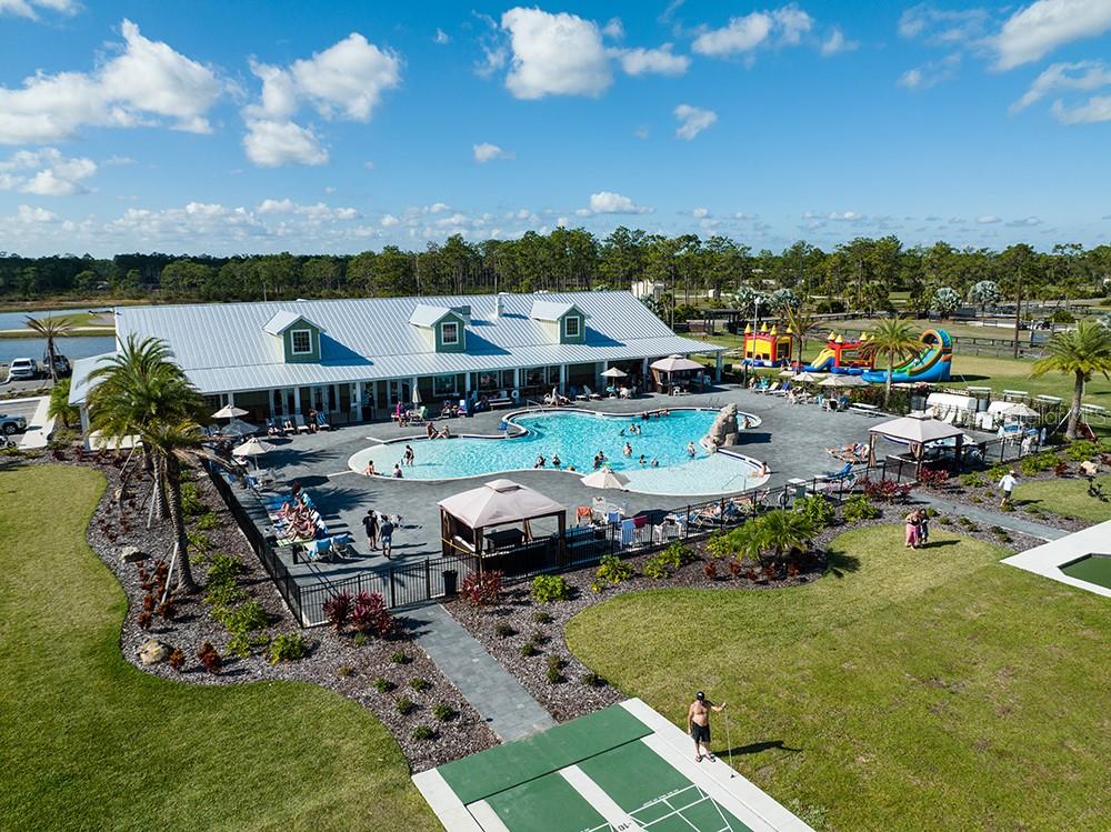 An aerial view shows a community clubhouse with a swimming pool, patio, and shuffleboard court — 54 TIKI TURN E, LAKE WALES, FL