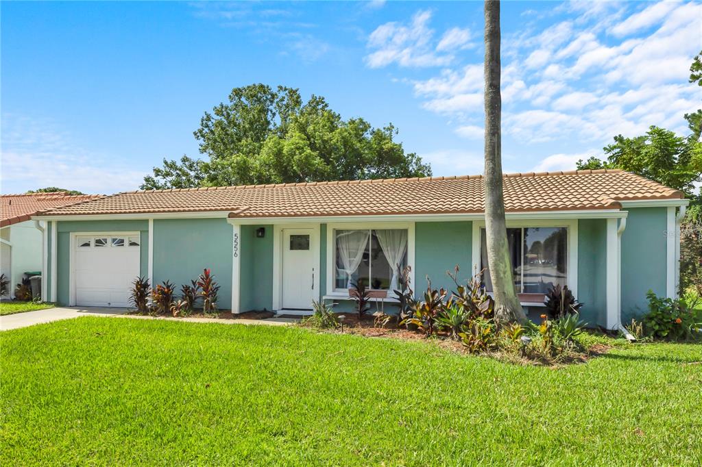 A single-story house with light blue siding, a white garage door, and a tiled roof — 5556 MEMORIAL DRIVE, ORLANDO, FL