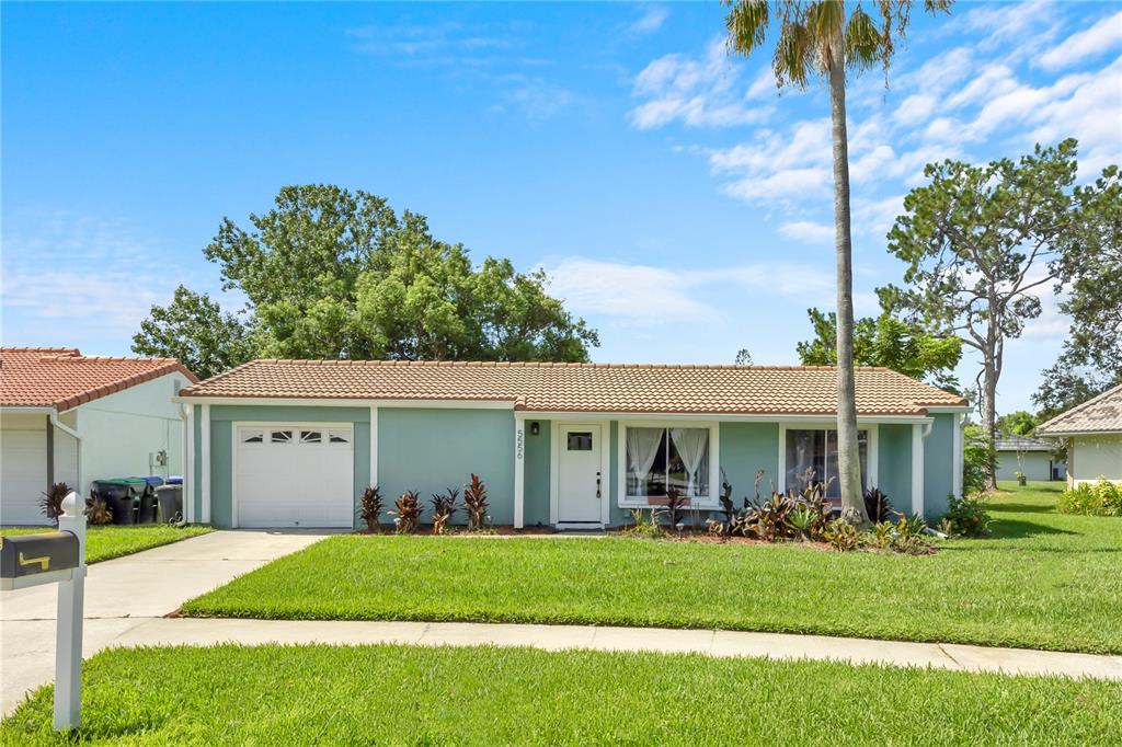 A single-story house with light green siding, a white garage door, and a tiled roof — 5556 MEMORIAL DRIVE, ORLANDO, FL