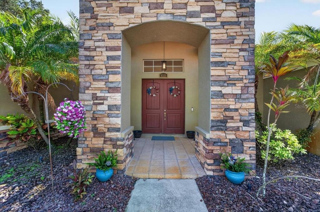 The front entrance of a house features a stone-clad archway and double red doors — 5325 LAKE SIENA DRIVE, WIMAUMA, FL