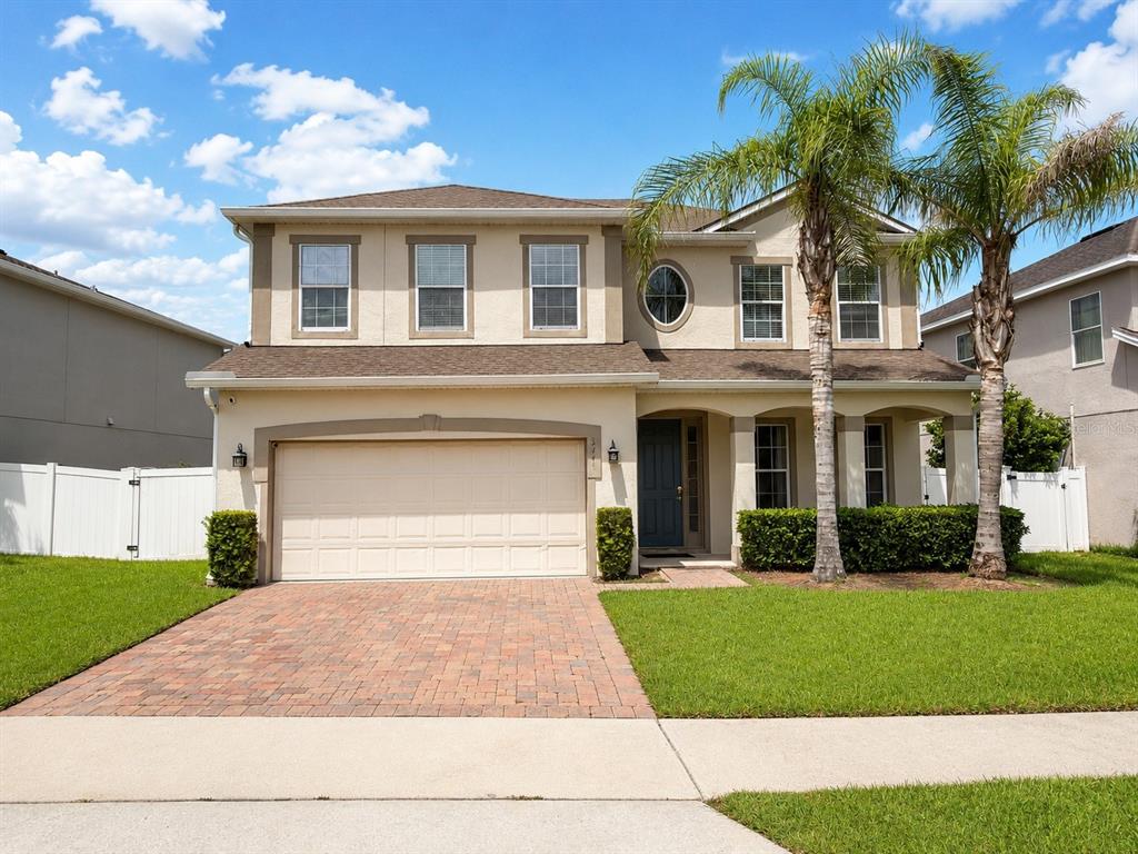 A two-story suburban house with a paved driveway, a two-car garage, and a palm tree — 3447 GRETCHEN DRIVE, OCOEE, FL