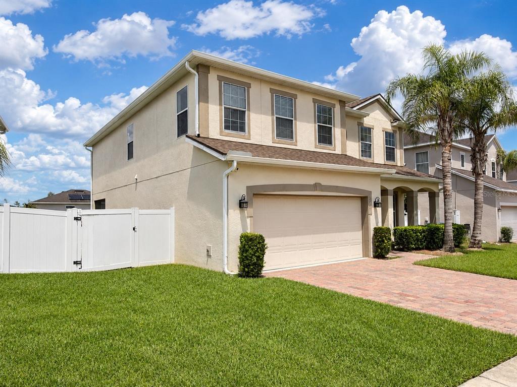 A two-story beige house with a two-car garage and a white vinyl fence — 3447 GRETCHEN DRIVE, OCOEE, FL