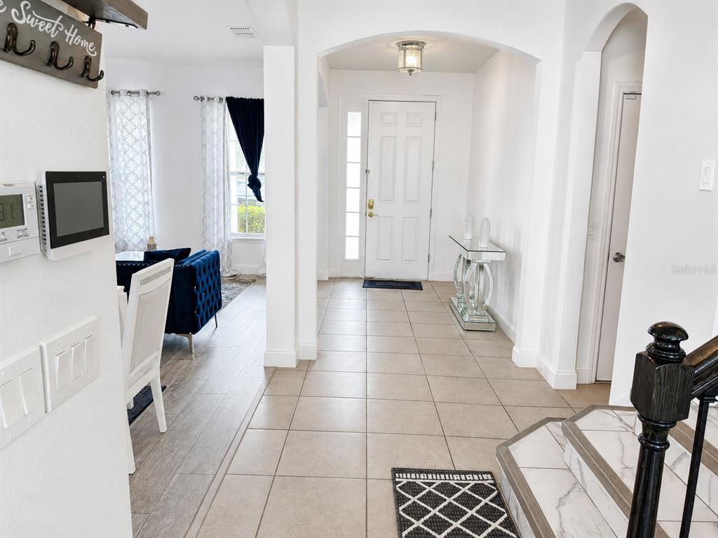 An entryway with tile flooring leads to a white front door and a living area — 3447 GRETCHEN DRIVE, OCOEE, FL