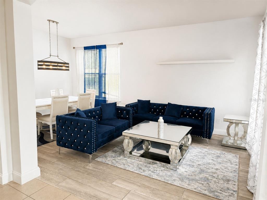 A living room and dining area feature blue tufted sofas, a mirrored coffee table, and tile flooring — 3447 GRETCHEN DRIVE, OCOEE, FL