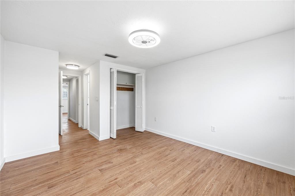 An empty bedroom with white walls, wood-look flooring, a ceiling fan, and a closet — 7328 MAKO DRIVE, HUDSON, FL