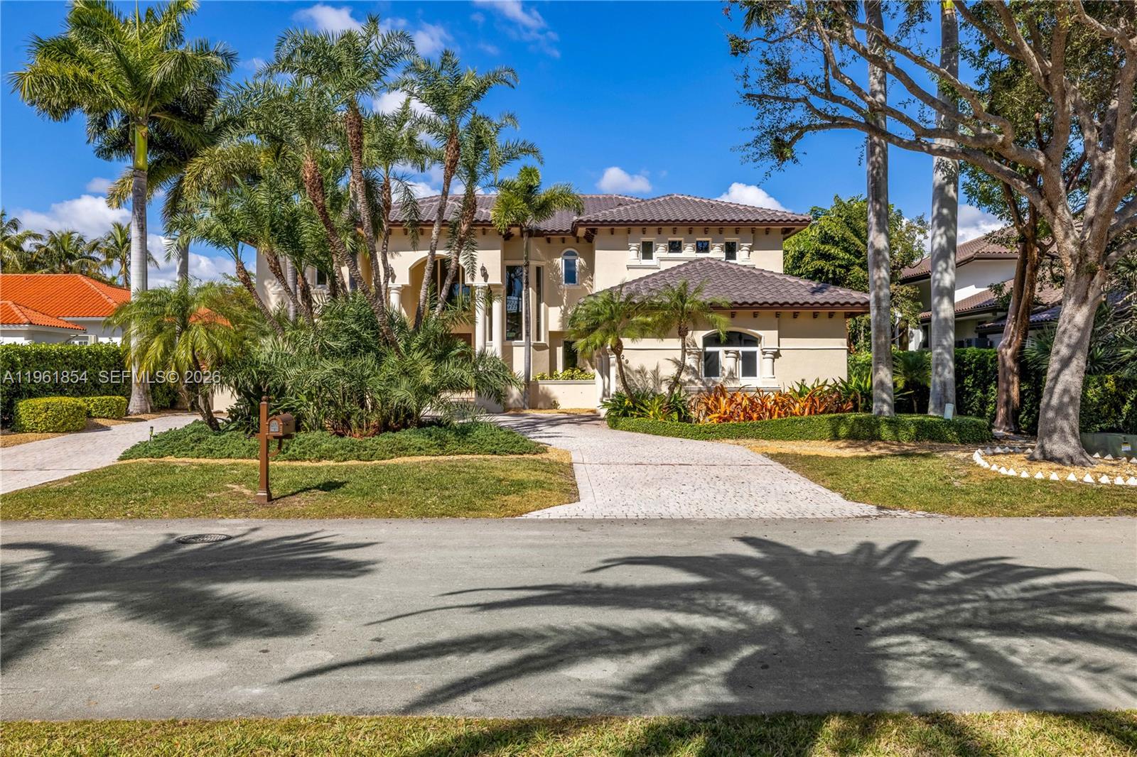 A two-story Mediterranean-style house with a tile roof, palm trees, and a paved driveway — 129 Gavilan Ave, Coral Gables FL 33143, CORAL GABLES, FL