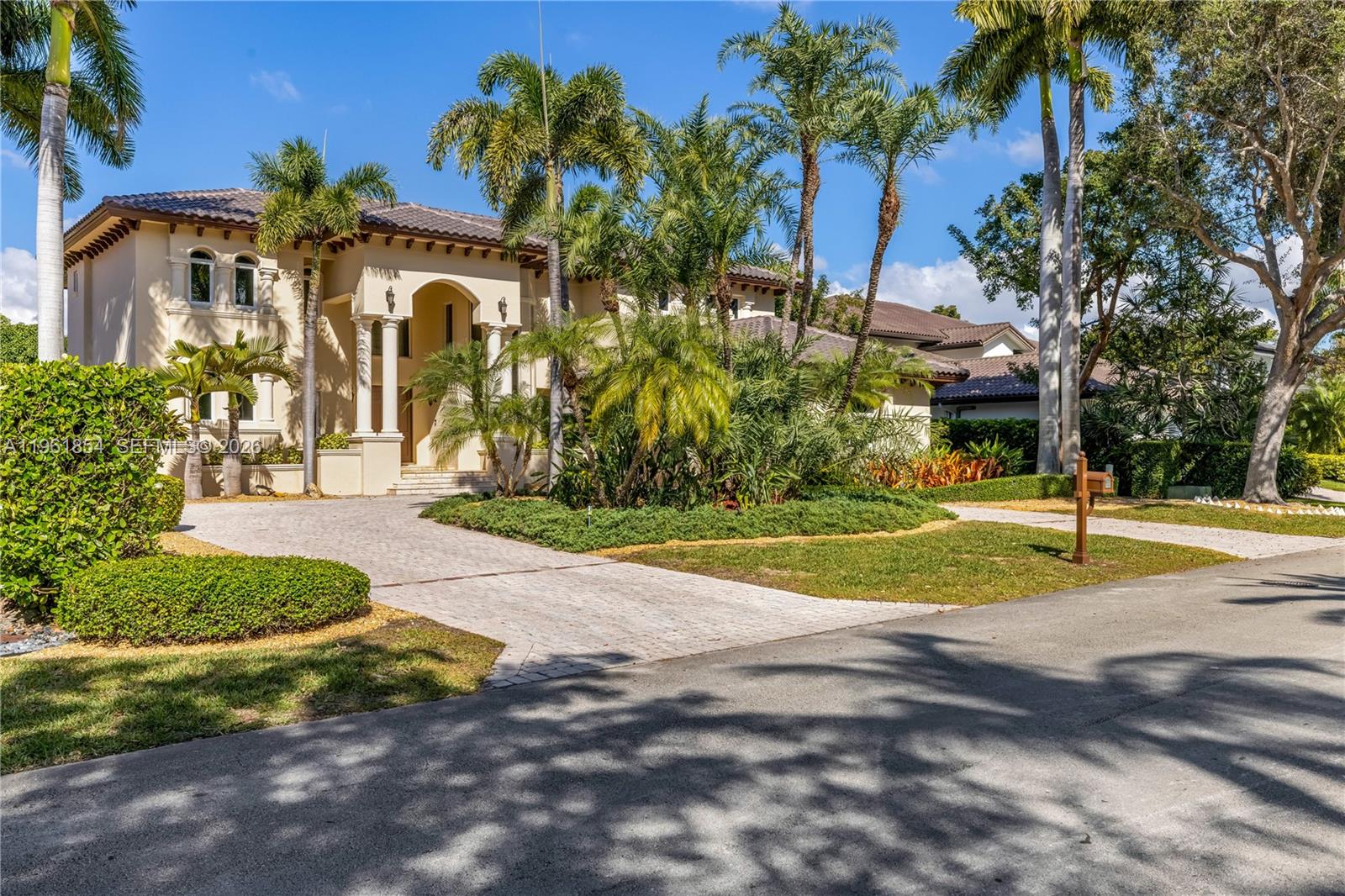 A two-story Mediterranean-style house with a paved driveway and palm trees in the front yard — 129 Gavilan Ave, Coral Gables FL 33143, CORAL GABLES, FL