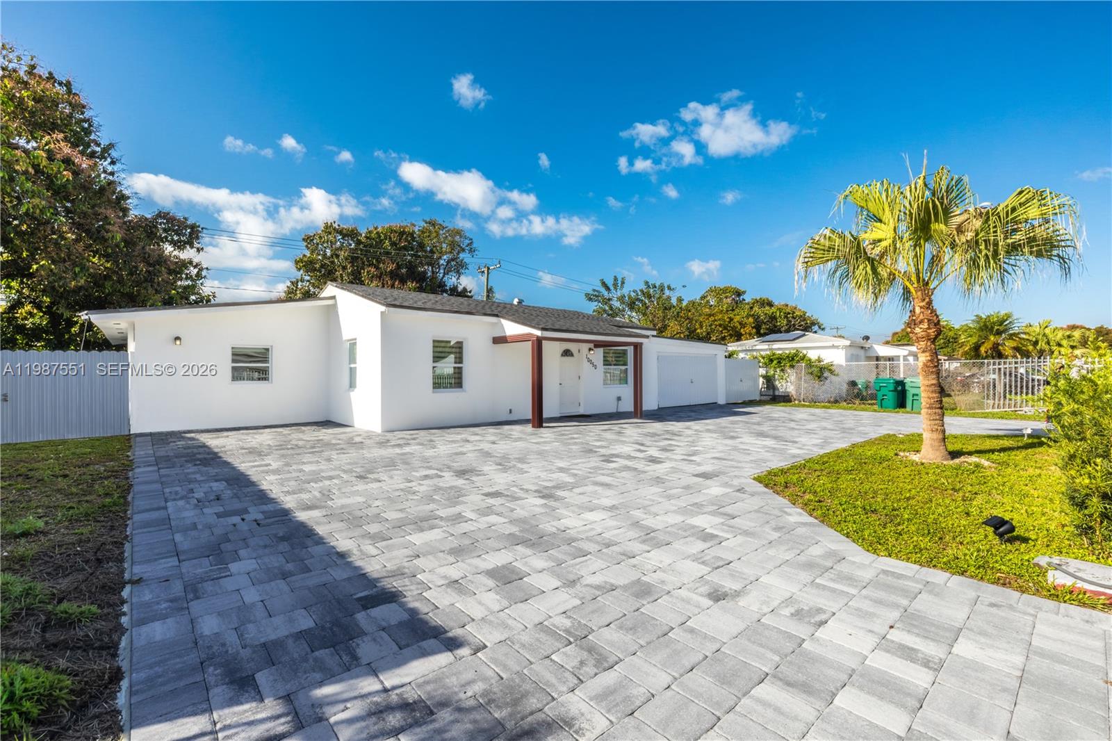 A white single-story house features a large gray paver driveway and a single palm tree — 10050 SW 171st St # 10050, Miami FL 33157, MIAMI, FL