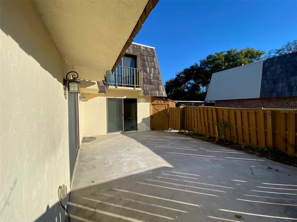 A concrete patio sits outside a two-story building with a wooden fence and balcony — 2911 PECAN AVENUE, LEESBURG, FL