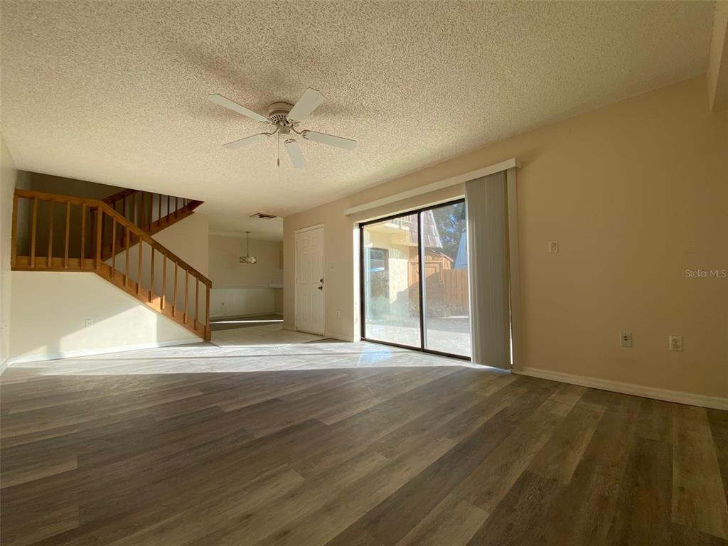 A living room features wood-look flooring, a staircase, a ceiling fan, and sliding glass doors — 2911 PECAN AVENUE, LEESBURG, FL