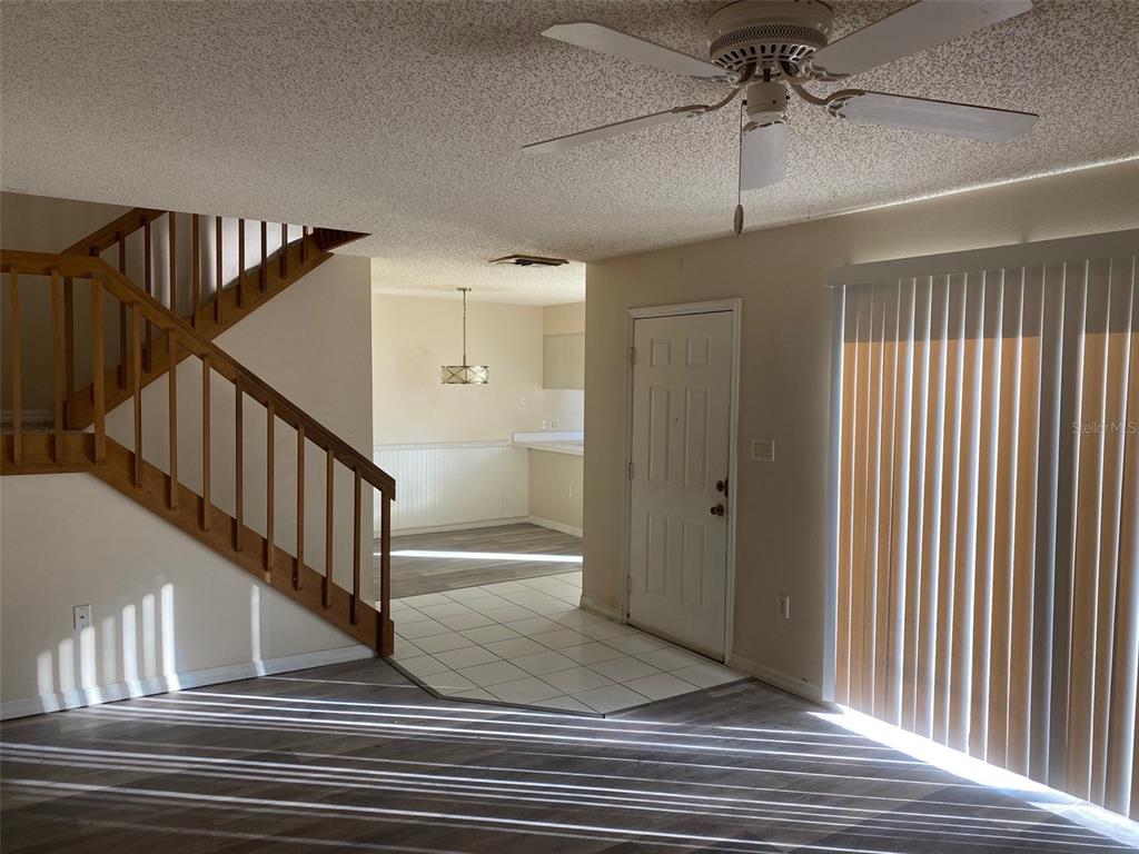 A living room features a wooden staircase, tile entryway, and a ceiling fan — 2911 PECAN AVENUE, LEESBURG, FL