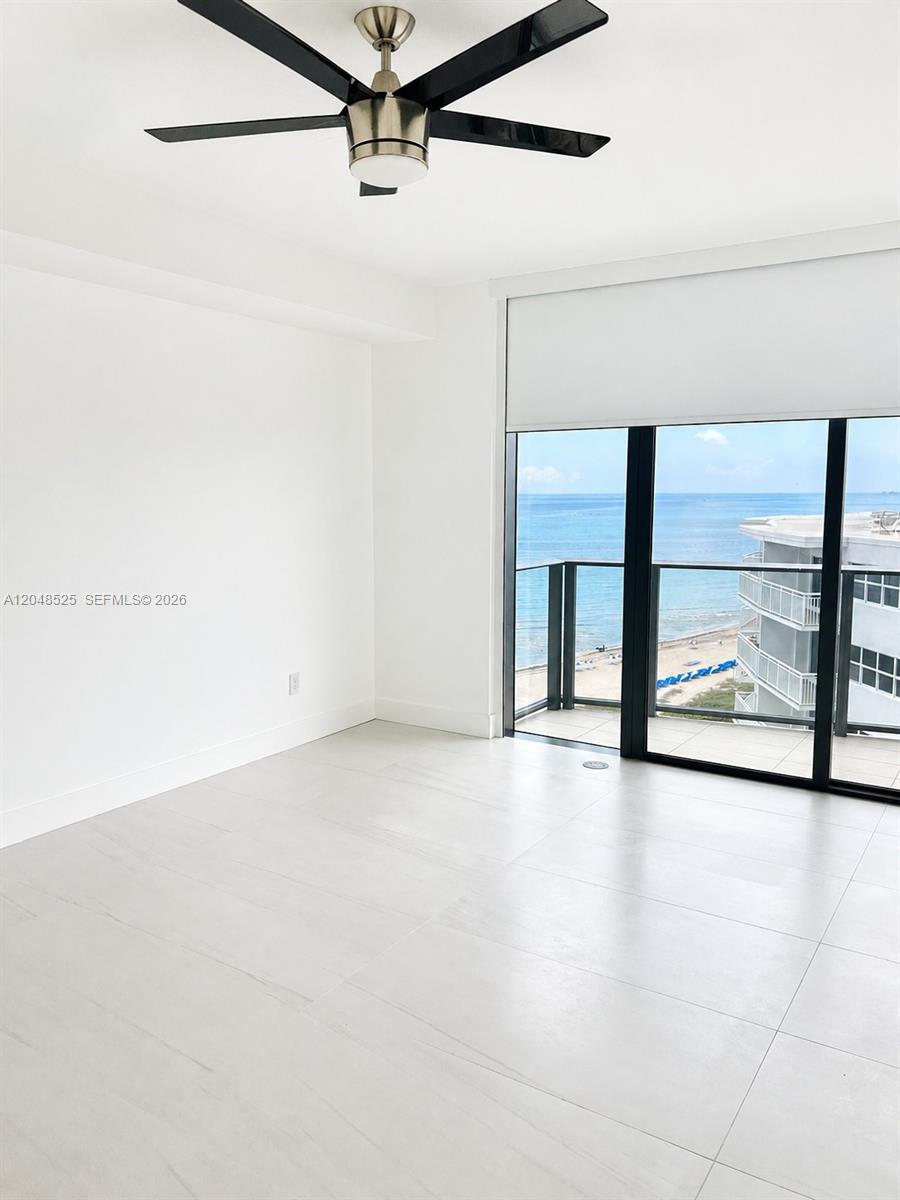 An empty room features white tile floors, a ceiling fan, and a balcony overlooking the ocean — 730 N Ocean Blvd # 1205, Pompano Beach FL 33062, POMPANO BEACH, FL