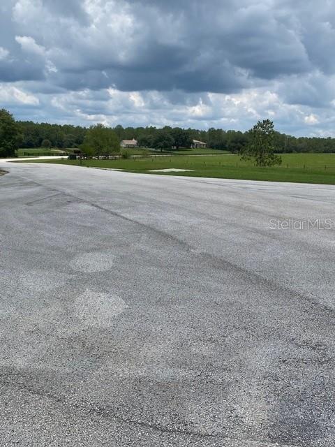 A paved road leads toward a grassy field with trees and a distant house — 5698 QUICKSILVER, FLORAL CITY, FL