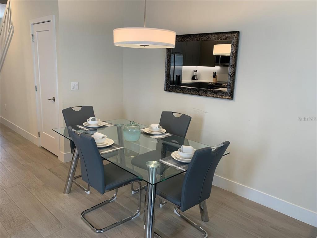 A dining area features a glass-topped table, four gray chairs, and a wall-mounted mirror — 17307 HIDDEN FOREST DRIVE, CLERMONT, FL