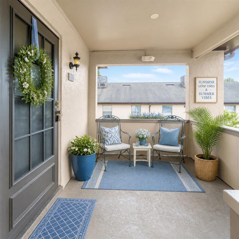 A covered porch features two metal chairs, a small table, and blue decor accents — 2415 NE 7TH STREET UNIT 8, OCALA, FL