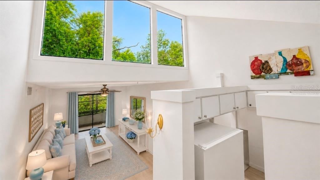 A high-ceilinged living room features large windows, white walls, and a balcony view — 2415 NE 7TH STREET UNIT 8, OCALA, FL