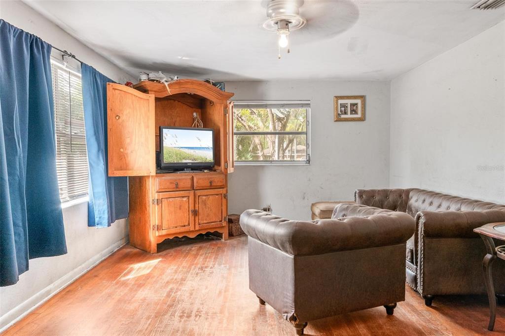 A living room features hardwood floors, a wooden entertainment center, and brown leather furniture — 4849 GRAND AVENUE, DE LEON SPRINGS, FL